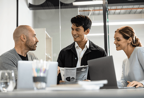 Business people having a casual work meeting with paperwork in front of a laptop screen to represent Brother's company policies