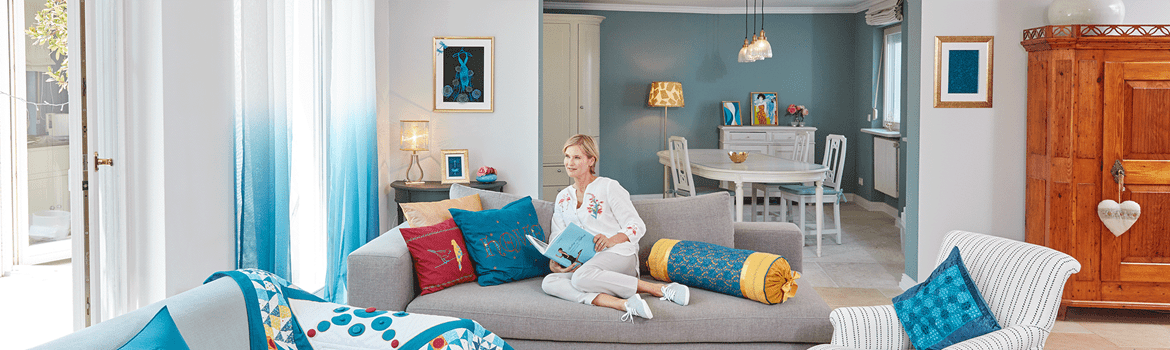 Living room with quilt, embroidered pillows and lady reading book